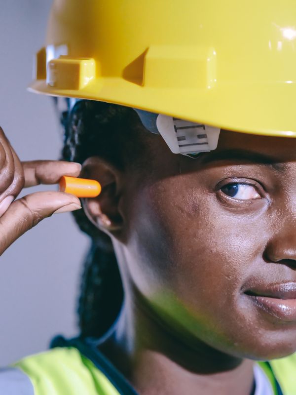 Worker inserting hearing protection earplugs on a job site